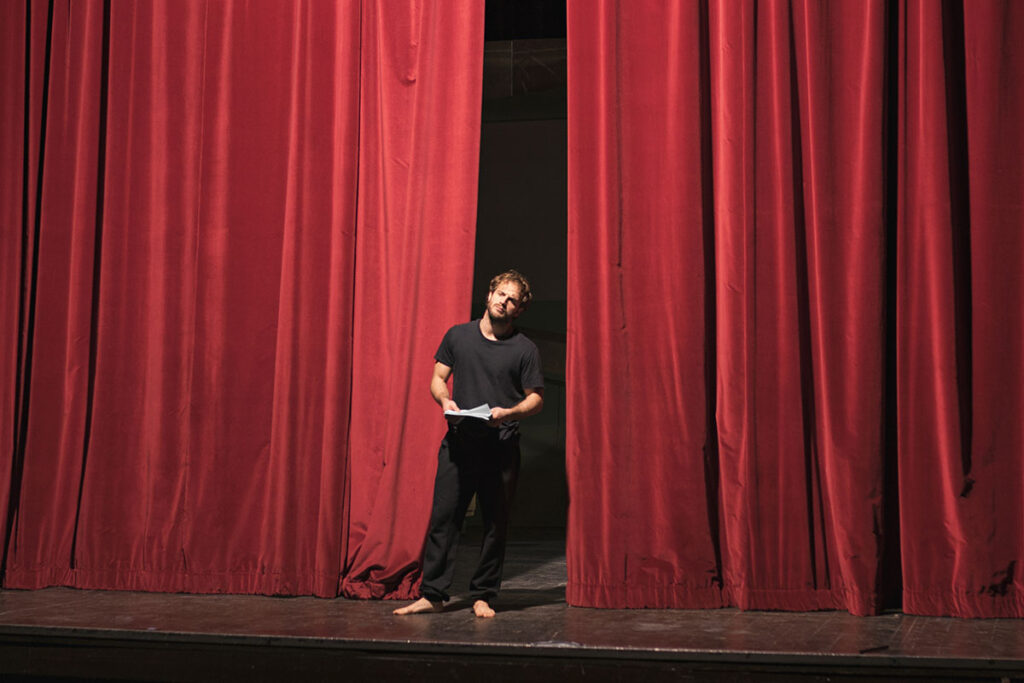 Man standing on stage in theater.